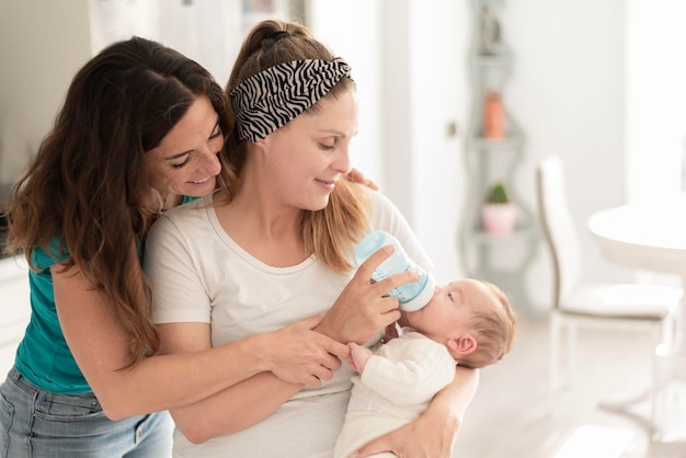 Een lesbisch stel dat een fles melk geeft aan hun baby, homohuwelijk, homo-ouders en adoptieconcept