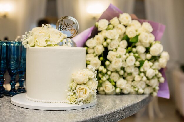 Foto een lichte verjaardagstaart versierd met witte bloemen op de achtergrond van het restaurant