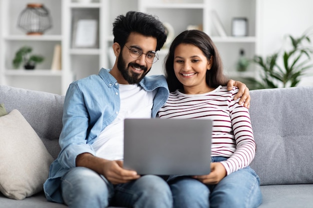 Een lief hindoe-paar kijkt thuis naar een film op een laptop.