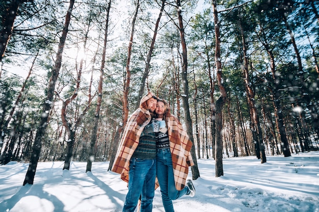 Een liefdevol jong stel rust in de bergen in een besneeuwd bos. concept gezamenlijke rust