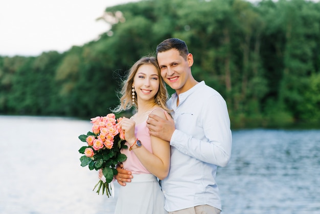 Een liefdevol koppel, een jongen en een meisje staan aan de oever van een rivier of meer