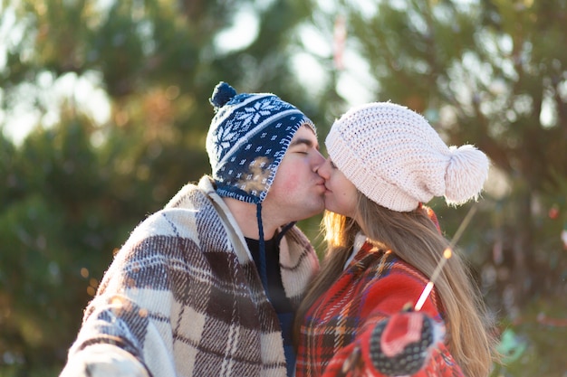 Een liefdevol koppel in warme plaids kussen met sterretjes in hun handen, maak kennis met de wintervakantie in een besneeuwd bos