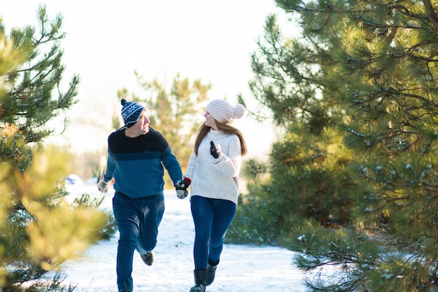 Een liefdevol paar hand in hand loopt door het de winterbos. Lach en heb een goede tijd