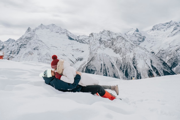 Een liefdevol stel in de winter in de sneeuw. Kus in de sneeuw in de bergen.