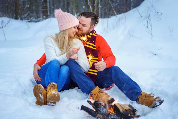 Een liefdevol stel in de winter in het bos bij het vuur met sterretjes in een omhelzing. Romantische relatie