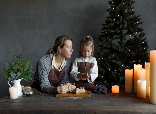 Een liefhebbende moeder met een dochtertje bereidt een kersttraktatie voor in de keuken en bereidt zich voor op de gezinsvakantie van Kerstmis