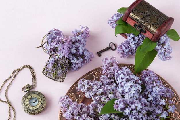 een lila boeket in een oude bronzen plaat, een bronzen kleine kooi, een zak oud horloge