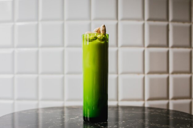 Een longdrinkcocktail in een groen longdrinkglas gegarneerd met pinda's