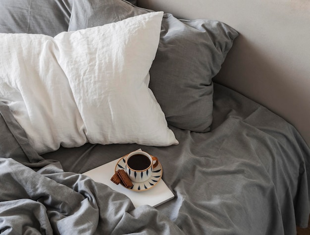 Een luie, ongehaaste weekendochtend Zwart koffiemagazine in bed met linnen beddengoed bovenaanzicht