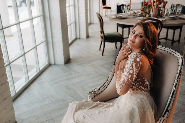 Een luxe bruid in een trouwjurk in de ochtend in haar interieur.