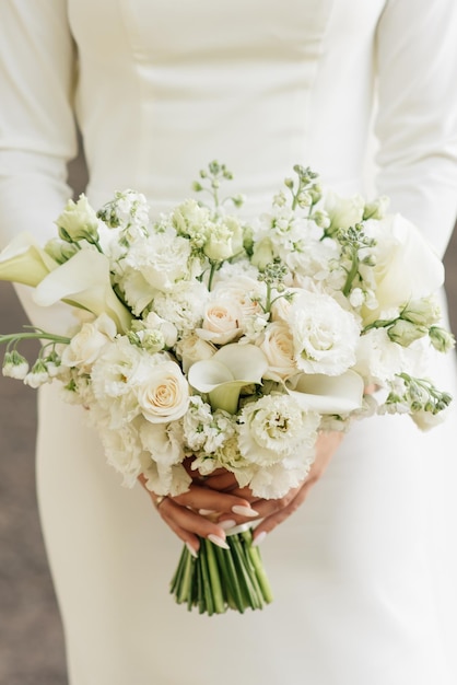 Een luxe bruidsboeket met witte rozen, anjers en koala's in de handen van de bruid