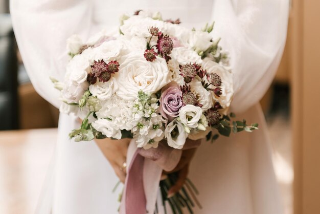 Een luxe bruidsboeket met witte rozen in de handen van de bruid