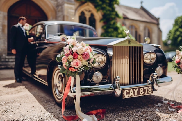 Foto een luxe zwarte trouwwagen versierd met bloemen en een strik wacht op het echtpaar buiten de kerk