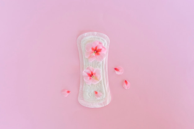 Een maandverband met bloemen erop ligt op een gele achtergrond. Menstruatie dagen. Hygiëne en versheid concept