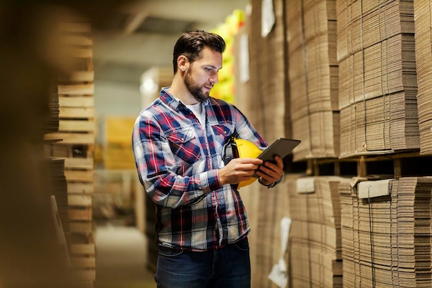 Een magazijnchef kijkt naar de tablet en controleert de inventaris