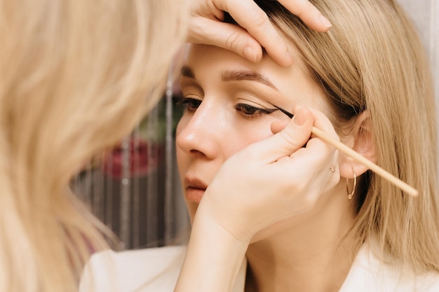 Een make-up artist meisje maakt een model Fotograferen in een schoonheidssalon