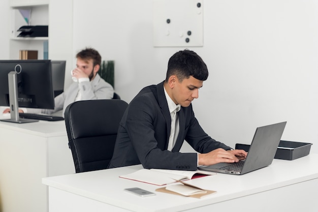 Een makelaar op de werkplek van het agentschap onderhandelt met de klant via internet en telefoon.