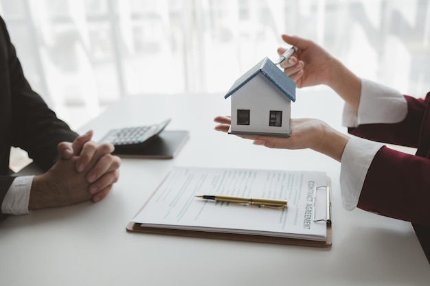 Een makelaar zit in haar kantoor de verkoper presenteert hoe het huis dat de klant gaat kopen eruit ziet de makelaar berekent de maandelijkse termijnbetalingen van de kopers