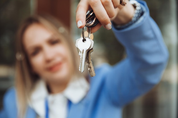 Een makelaarsvrouw heeft de sleutel tot een appartement in een nieuw huis, de eigenaar van het onroerend goed maakt een verkoop en koopt het concept van een onroerendgoedtransactieclose-up