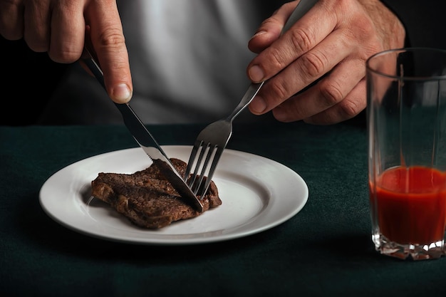 Een man aan het diner bestaande uit een heerlijke gegrilde biefstuk en knalrood tomatensap