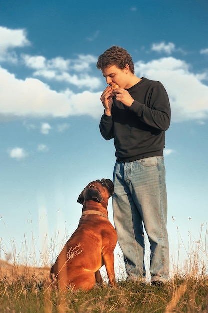 een man aan het wandelen met een hond eet een hamburger, vraagt de hond ook