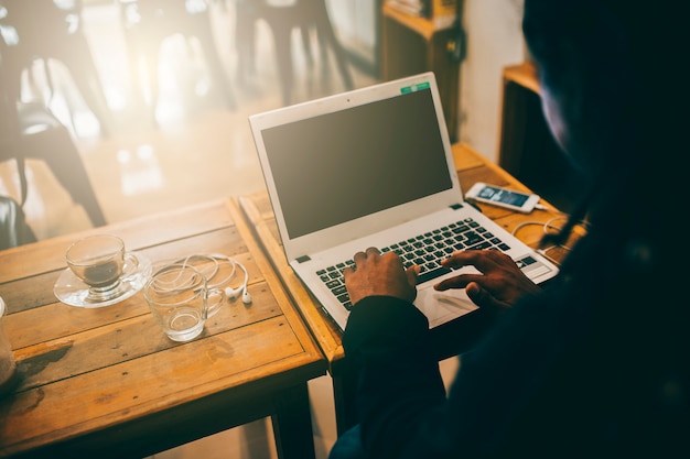 Een man aan het werk op laptop zittend aan een koffie winkel