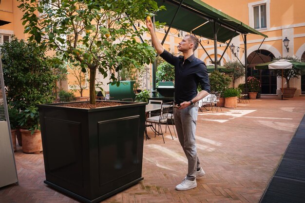 Foto een man bewondert een citroenboom in de binnenplaats van een luxe hotel in rome