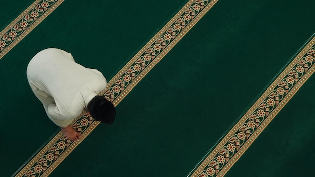 Een man bidt op een gebedskleed in een tempel.