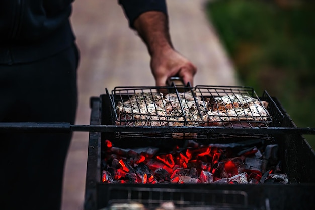 een man braadt buiten grote sappige stukken vlees op de grill op brandende kolen