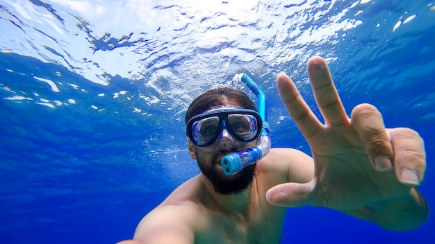 Een man die aan het snorkelen is, zwemt in het onderwaterkoninkrijk van de Rode Zee en probeert naar de oppervlakte te komen