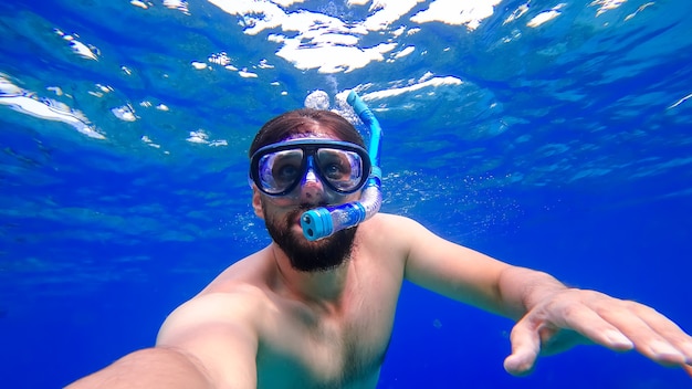 Een man die aan het snorkelen is, zwemt in het onderwaterkoninkrijk van de Rode Zee en probeert naar de oppervlakte te komen