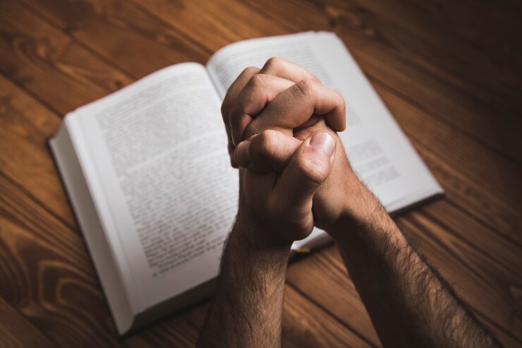 Foto een man die bidt op een boek op een donkere ondergrond
