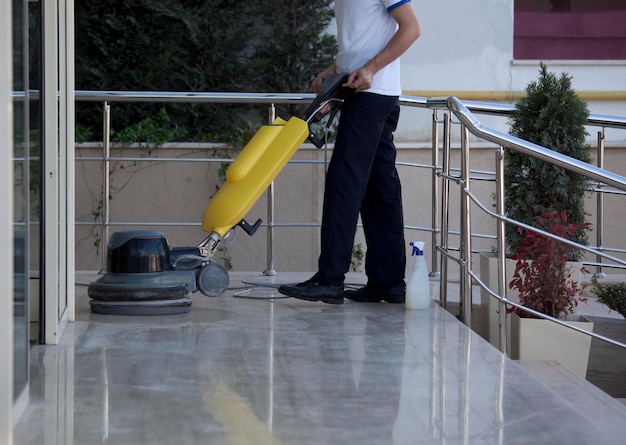 Een man die de vloer schoonmaakt met een afbeelding van een scrubbermachine