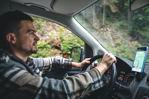 Een man die een auto bestuurt, rijdt in een bergachtig bosgebied