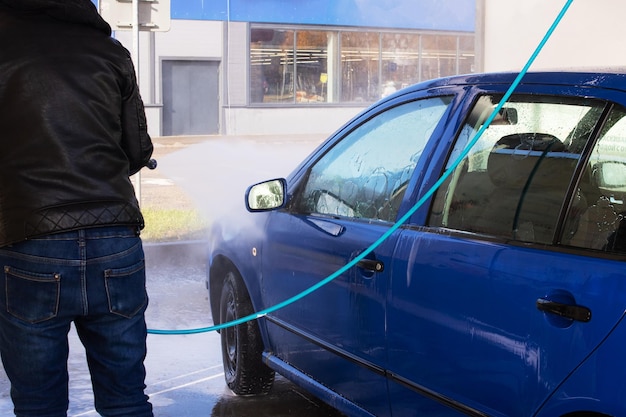 Een man die een auto wast bij een wasstraat