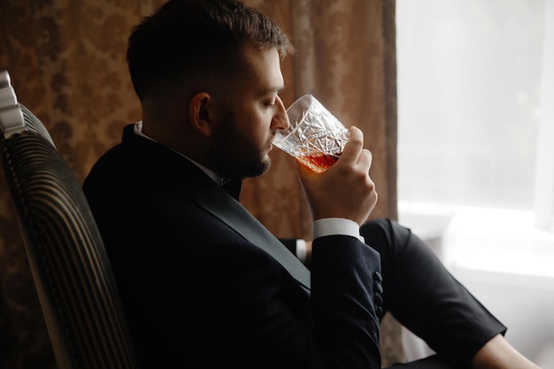 Een man die een glas whisky drinkt.