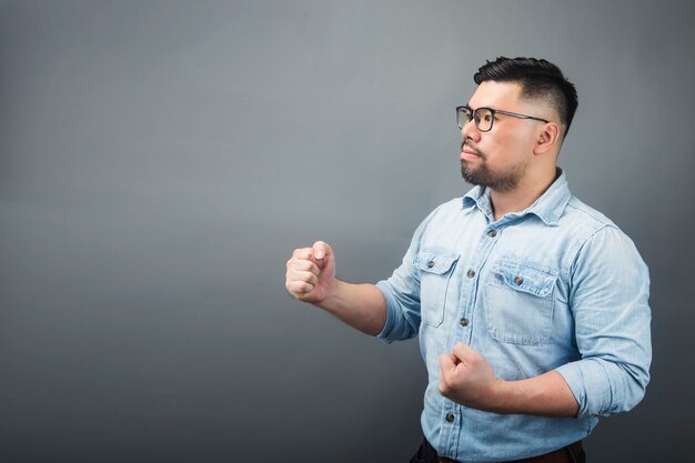 Een man die een overwinningsteken op een grijze achtergrond doet