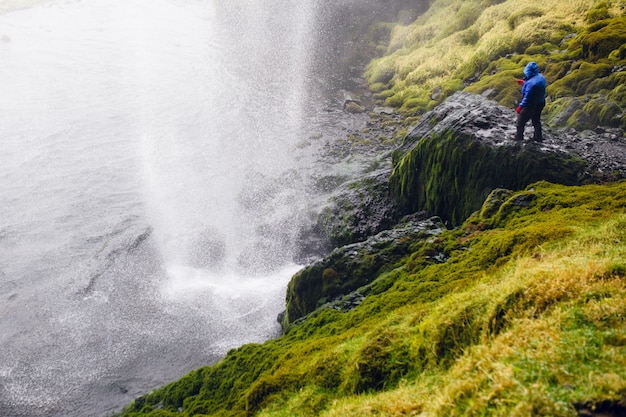 Een man die een reiziger is op een achtergrond van een ijslandse waterval