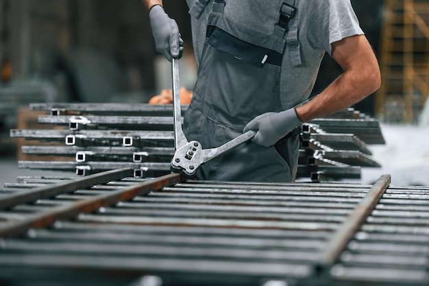 Een man die in de fabriek werkt, snijdt met de knipper het metaalproduct van dichtbij