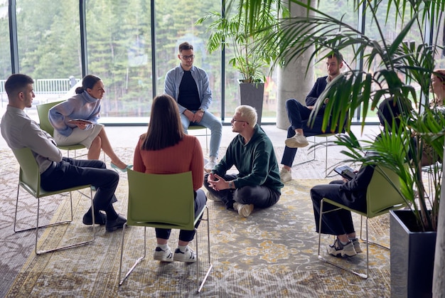 Een man die in het midden van een cirkel zit en zijn zakelijke ideeën gepassioneerd deelt met zijn collega's en een sfeer van samenwerking en innovatie bevordert op een dynamische en boeiende werkplek