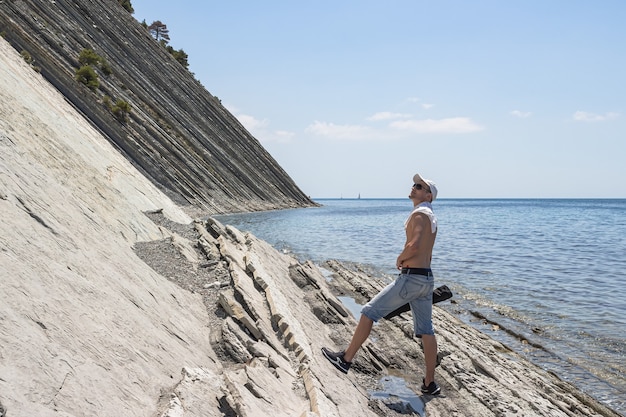 Een man die langs het wilde stenen strand liep, stopte en kijkt omhoog. De badplaats Gelendzhik. Rusland, kust van de Zwarte Zee