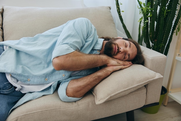 Een man die overdag op de bank slaapt, is moe en ontspannen na stress en een slecht gevoel. Stress op het werk, slecht slapen en gezondheidsproblemen