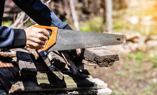 Een man die overdag planken in de tuin zaagt