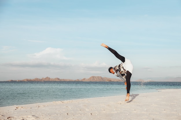 Een man die taekwondo-kick vechtsport traint op het strand