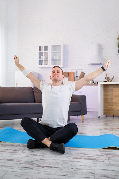 Een man die thuis yoga-oefeningen doet, zittend op de vloer van de woonkamer. Gezonde levensstijl.