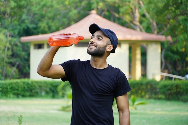 Een man die water drinkt in het park