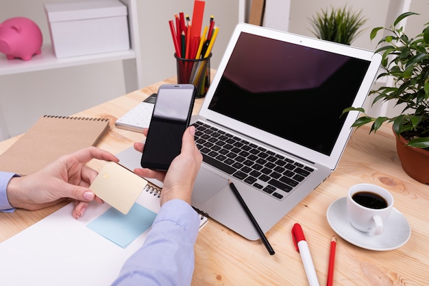 Een man die werkt met laptop, rekenmachine, pennen, potloden, kaart, telefoon en een plant op zijn bureaublad in zijn kantoor