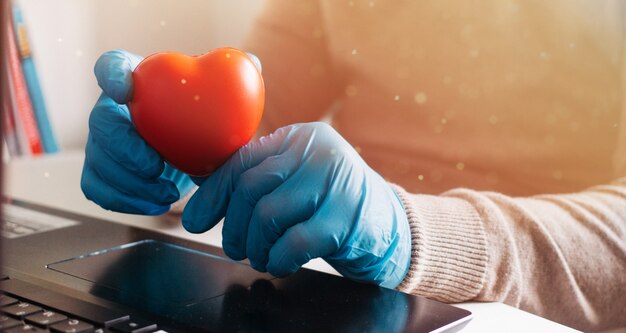 Een man die werkt vanuit huis op een laptop met wegwerphandschoenen ter bescherming. Corona-uitbraak. In quarantaine geplaatste zakenman. Thuiswerken. Blijf thuis.