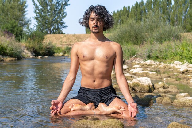 Een man die yoga doet in de rivier