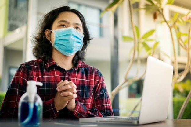 Een man draagt een chirurgisch masker en bidt met hoop tijdens covid19 of verspreiding van het coronavirus